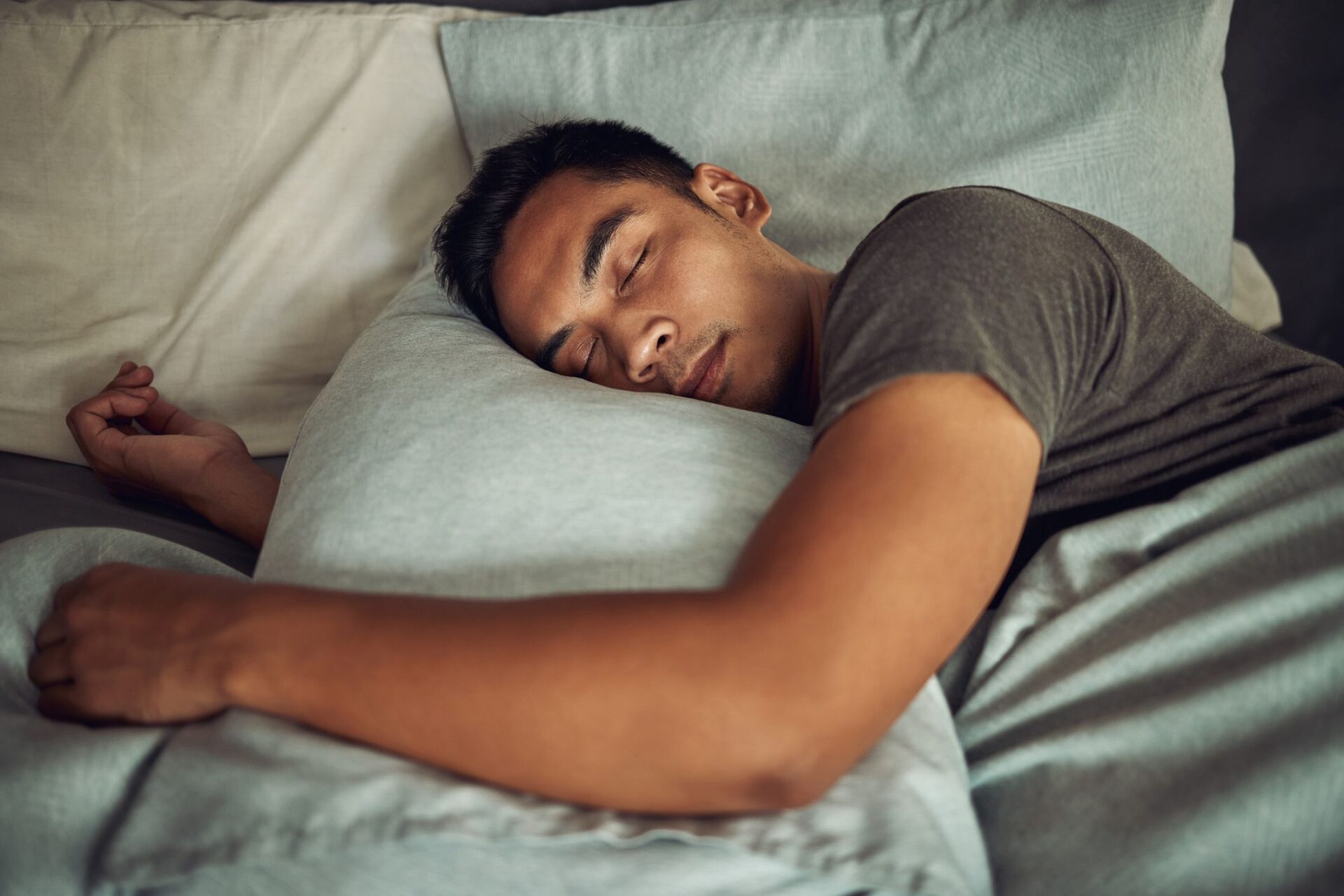 Foto de un joven durmiendo tranquilamente en la cama de su casa.