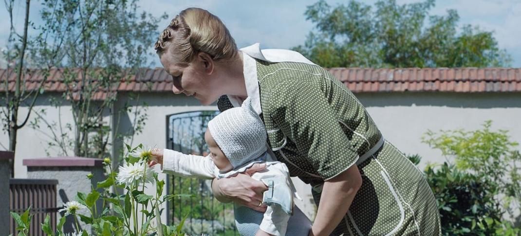 una mujer sosteniendo un bebé frente a una planta