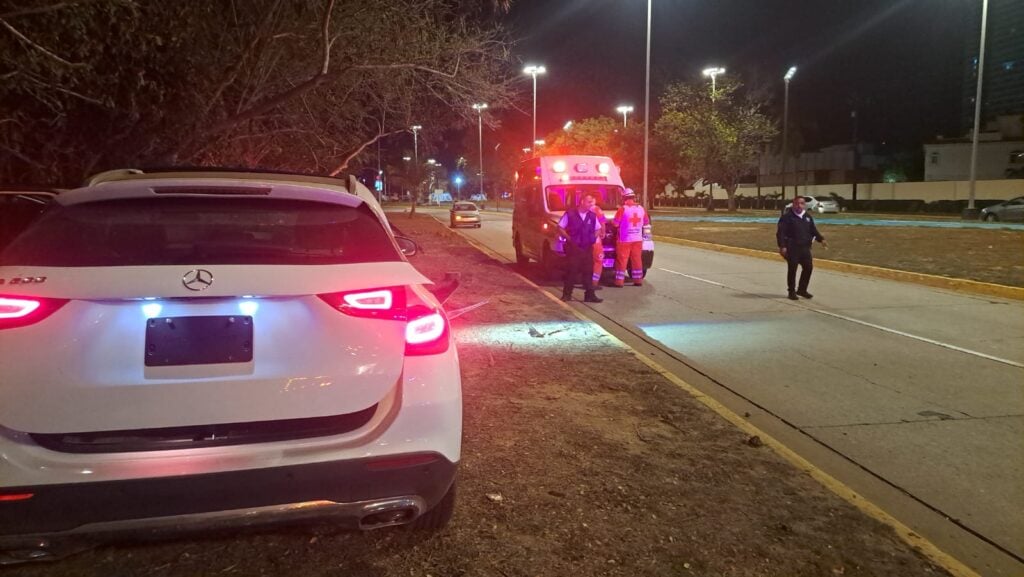 Camioneta accidentada sobre el camellón. Hay una ambulancia al fondo