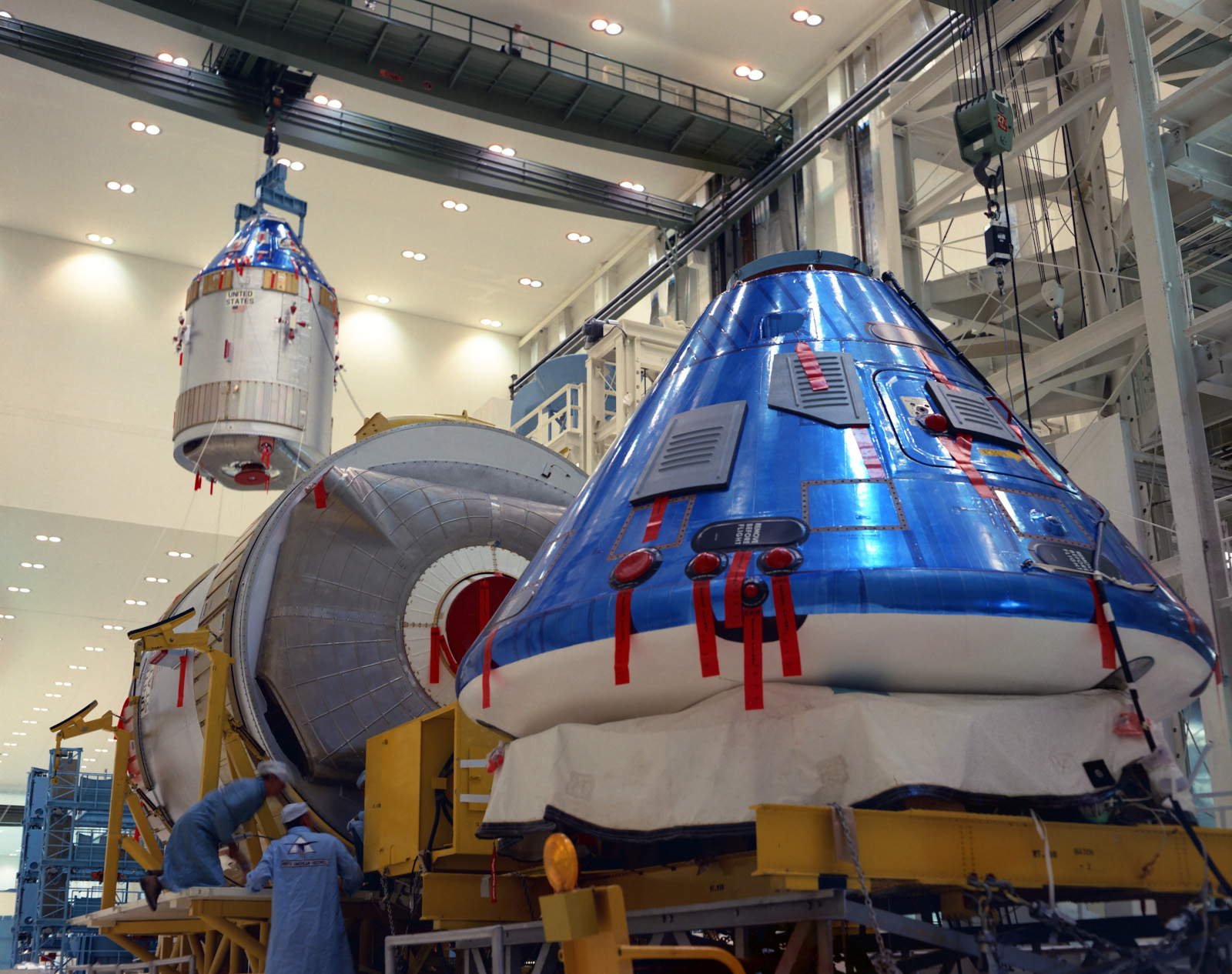 En el edificio de operaciones de naves espaciales tripuladas del KSC, los trabajadores desempaquetan los módulos de comando y servicio del Apolo 12, en primer plano, mientras continúan trabajando en la nave espacial Apolo 11.