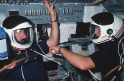 Los astronautas STS-41C James D. “Ox” Van Hoften, izquierda, y George D. “Pinky” Nelson usan sus cascos de lanzamiento y entrada durante la respiración previa a la primera caminata espacial.