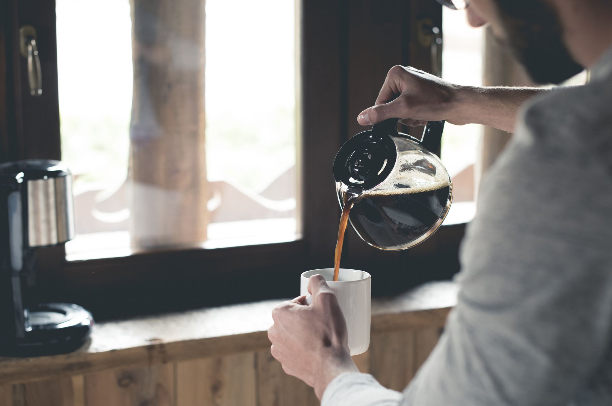 Un joven sirviendo café en una taza en casa