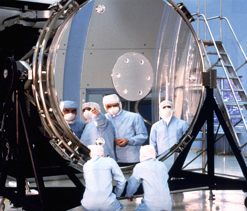 Los trabajadores inspeccionan el espejo primario de 94 pulgadas de diámetro del Telescopio Espacial Hubble antes del montaje.