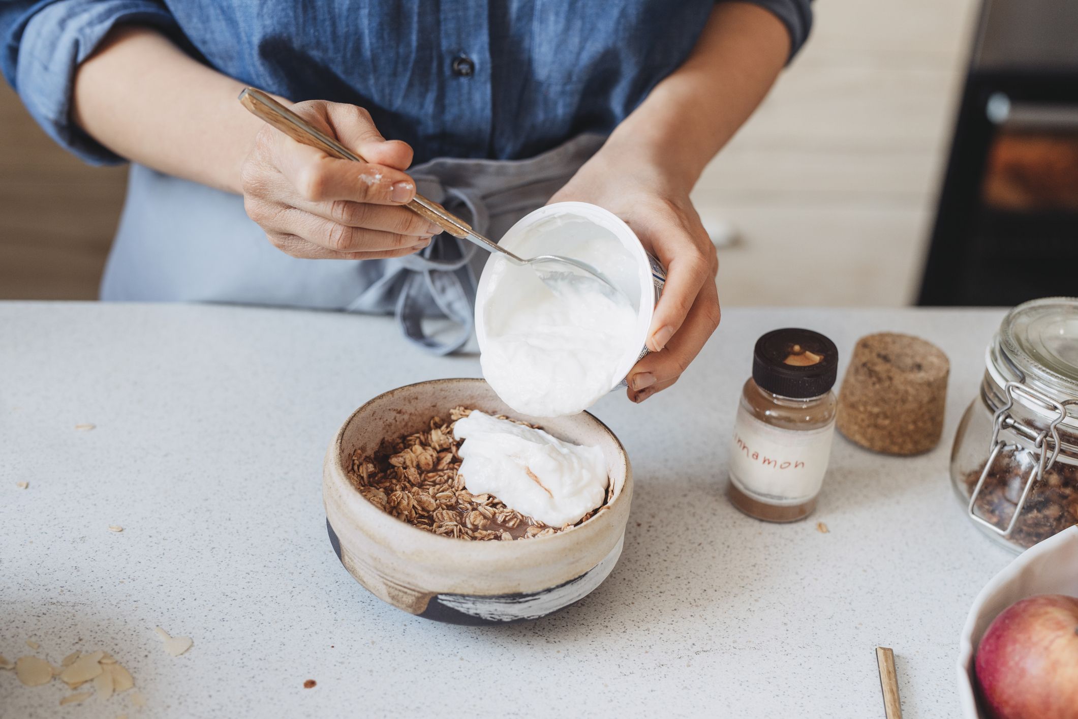 manos de una mujer añadiendo yogur griego a copos de avena, concepto de desayuno saludable