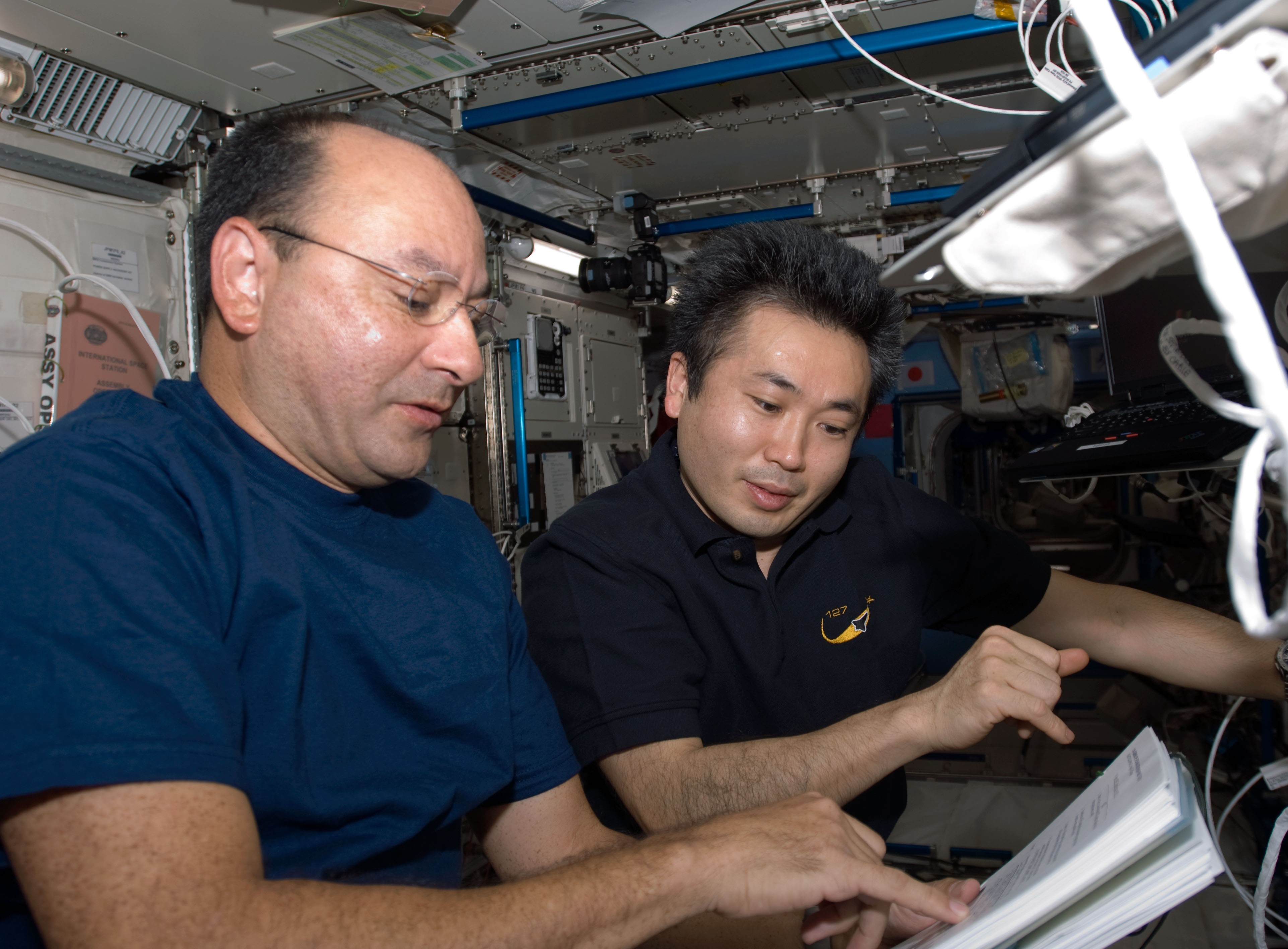 Mark J. Polansky, a la izquierda, y Koichi Wakata de la Agencia de Exploración Aeroespacial de Japón, uno de los tres equipos que transfirieron las cargas útiles de EF utilizando el brazo robótico de Kibo